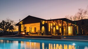 A modern house with a pool, featuring a covered patio and outdoor seating area. - Luxury Spa home w/ Entertainers Pool, hot tub & fire pits! (Yucca Valley)