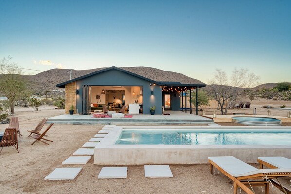 A modern house with a swimming pool, outdoor seating, and a patio area.