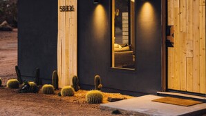 A modern building with a dark facade, a wooden door, and a number "58836" on the wall. - Luxury Spa home w/ Entertainers Pool, hot tub & fire pits! (Yucca Valley)