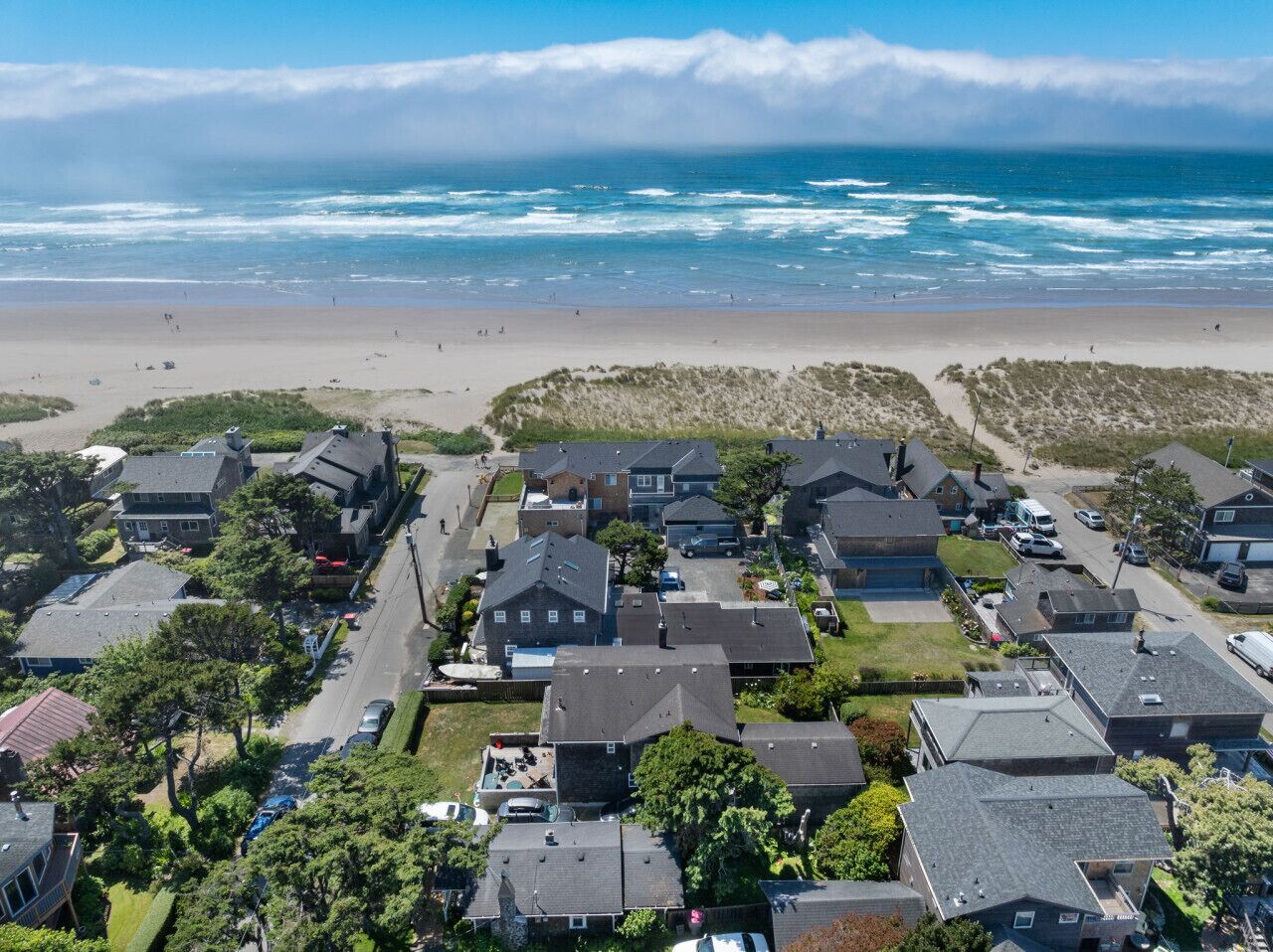 Vue aérienne d’une zone résidentielle côtière, avec des maisons, une plage et l’océan.
