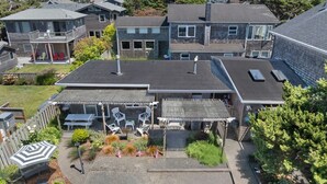 A multi-story building with a flat roof, outdoor seating area, and a fenced patio. - 1 Sandals Spa Suite: Intimate Getaway | Steps to Beach | Dog-Friendly (Cannon Beach)