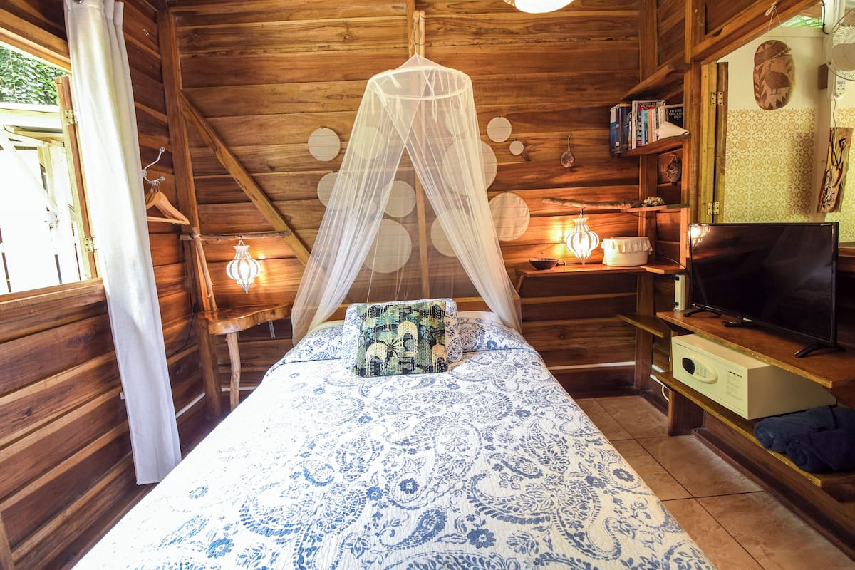 Una habitación de madera con una cama, un televisor y una estantería.