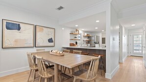 Una cucina moderna con un tavolo da pranzo in legno e sedie, un'isola nella cucina e vista sull'area pranzo adiacente.