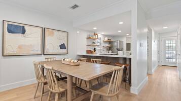 Une cuisine moderne avec une table et des chaises en bois, un îlot central et une vue sur la salle à manger adjacente.