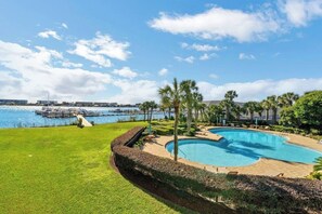 A swimming pool with a view of the marina and a grassy area.