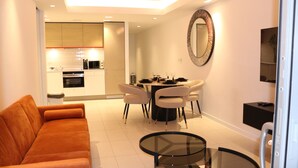 A modern living room with a sofa, a glass coffee table, and a dining area with a table set for four.