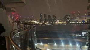 A nighttime cityscape with a view of a waterfront area and a busy road below.