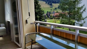 Ein Balkon mit Blick auf eine grüne Landschaft und Häuser.