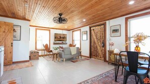 A spacious living room with a wooden ceiling, a sofa, a coffee table, and a TV. - Quaint Cottage Downtown Buckner (Buckner)