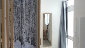 Um quarto com uma janela grande, um espelho e uma cortina estampada.