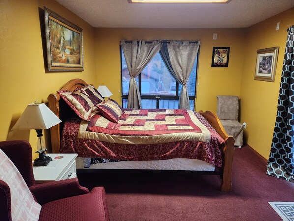 A bedroom with a bed, a chair, a desk, a lamp, a window with curtains, and a painting on the wall. - Charming tranquil 1 Bedroom Suite plus,full bathroom in  Villa  at Prescott,AZ 
 (Prescott)