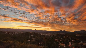 Une vue panoramique d’un paysage au coucher du soleil, avec une ville située dans la vallée et des montagnes lointaines.