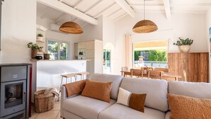 A modern living room with a sofa, a fireplace, and a dining area with a table and chairs. - Casa Vinti - Vue mer et montagne, piscine (Grosseto-Prugna)