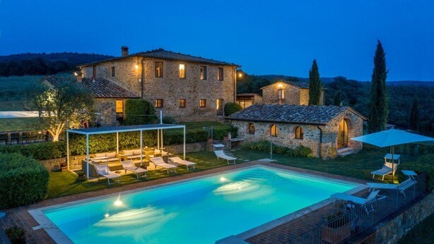 A stone villa with a swimming pool, outdoor seating, and a covered patio area.