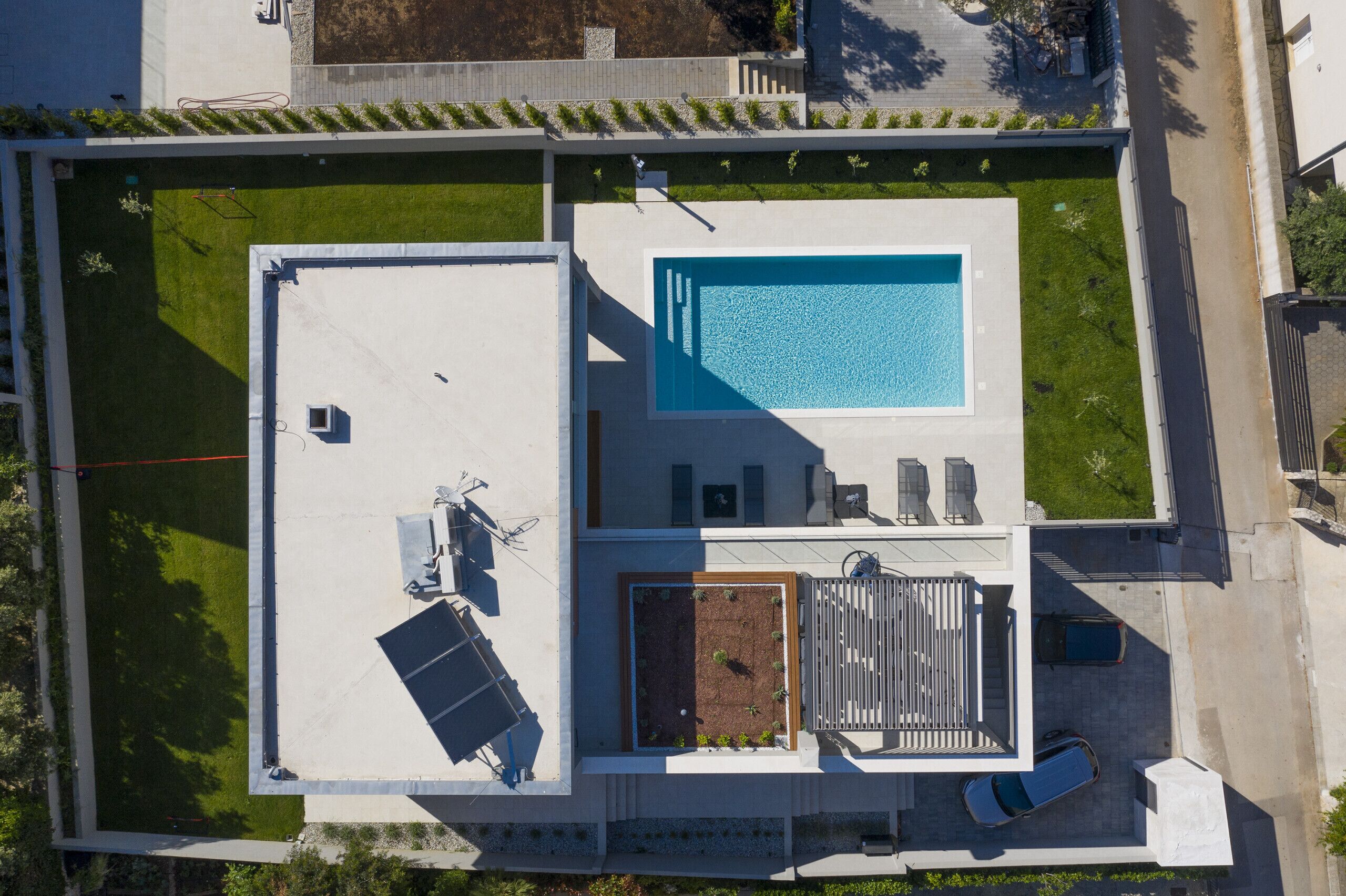An aerial view of a rooftop with a swimming pool, a garden area, and a covered patio with seating.