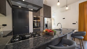 A modern kitchen with a central island, built-in oven, and stainless steel appliances.