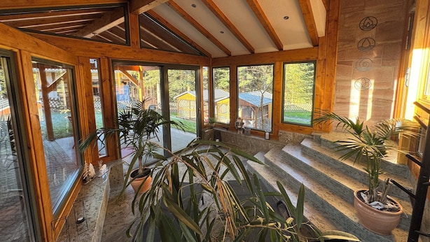 A spacious room with wooden beams, large windows, and potted plants. - Recreation in the forest - with swimming pool! (Heßles)