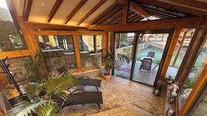 A spacious indoor area with a stone floor, wooden beams, and large windows offering views of the outdoors. - Recreation in the forest - with swimming pool! (Heßles)