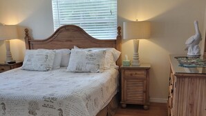 A bedroom with a wooden bed, two bedside tables with lamps, a nightstand, and a dresser. - Charming 3-bedroom house in quaint Venice with heated pool! (Venice)