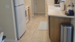 A kitchen with a refrigerator, sink, and cabinets. - Charming 3-bedroom house in quaint Venice with heated pool! (Venice)