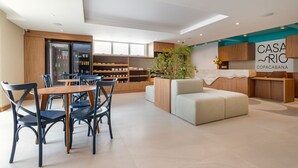 A modern hotel lobby with a reception desk, seating area, and a kitchen in the background.