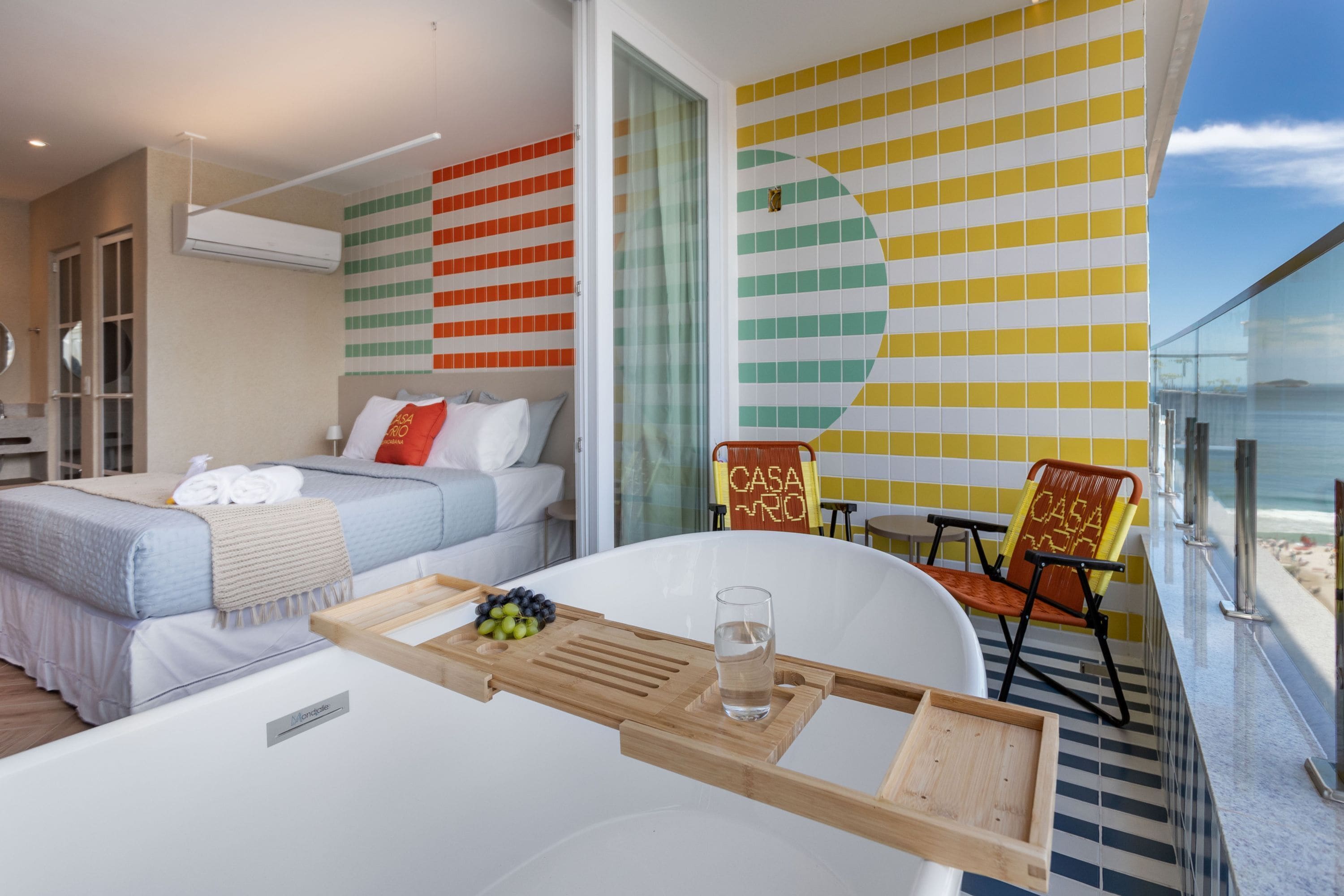 A modern hotel room with a bed, a dining table with a tray, and a chair.