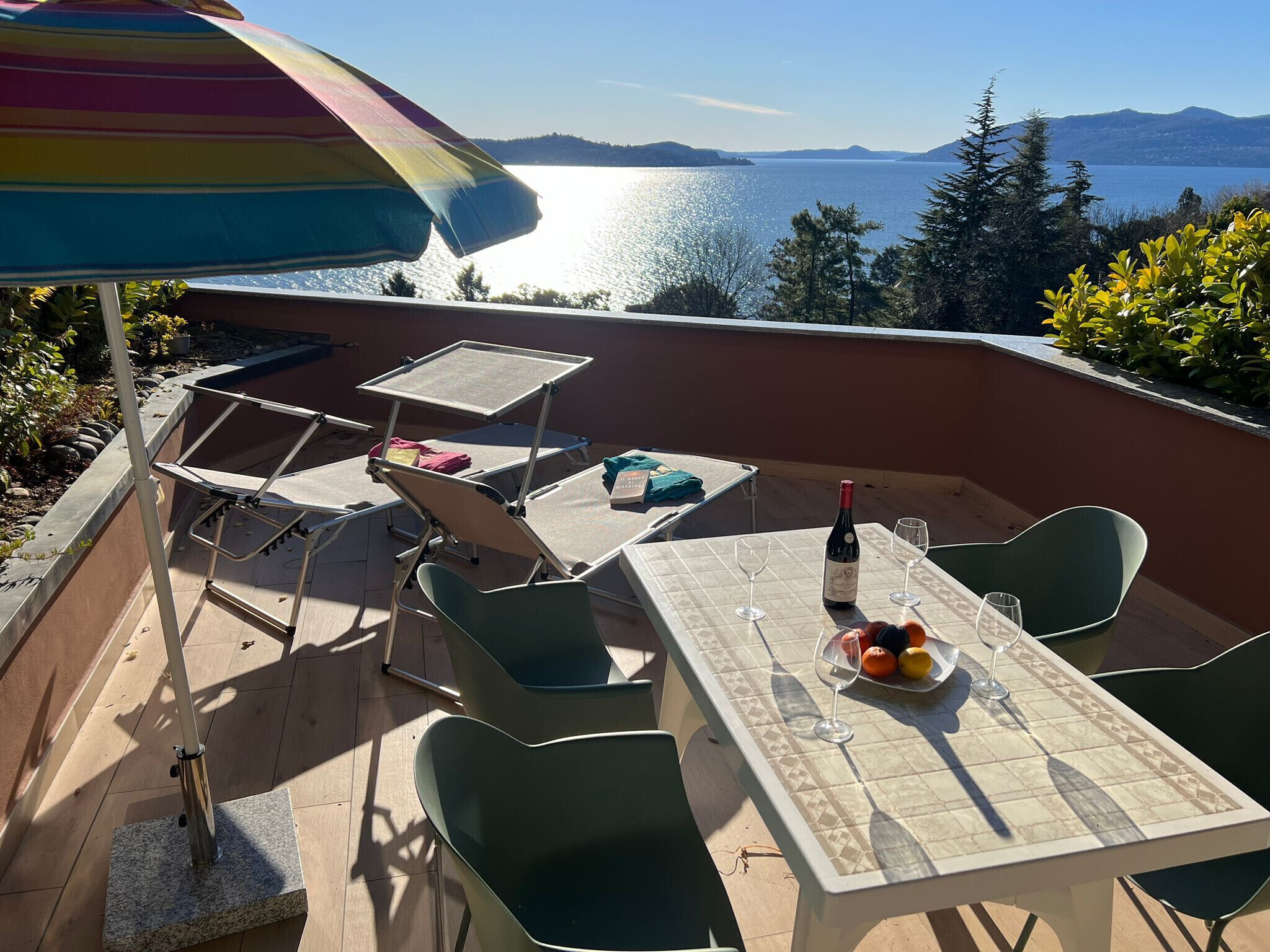 Une terrasse extérieure avec une table, des chaises et un parasol coloré.