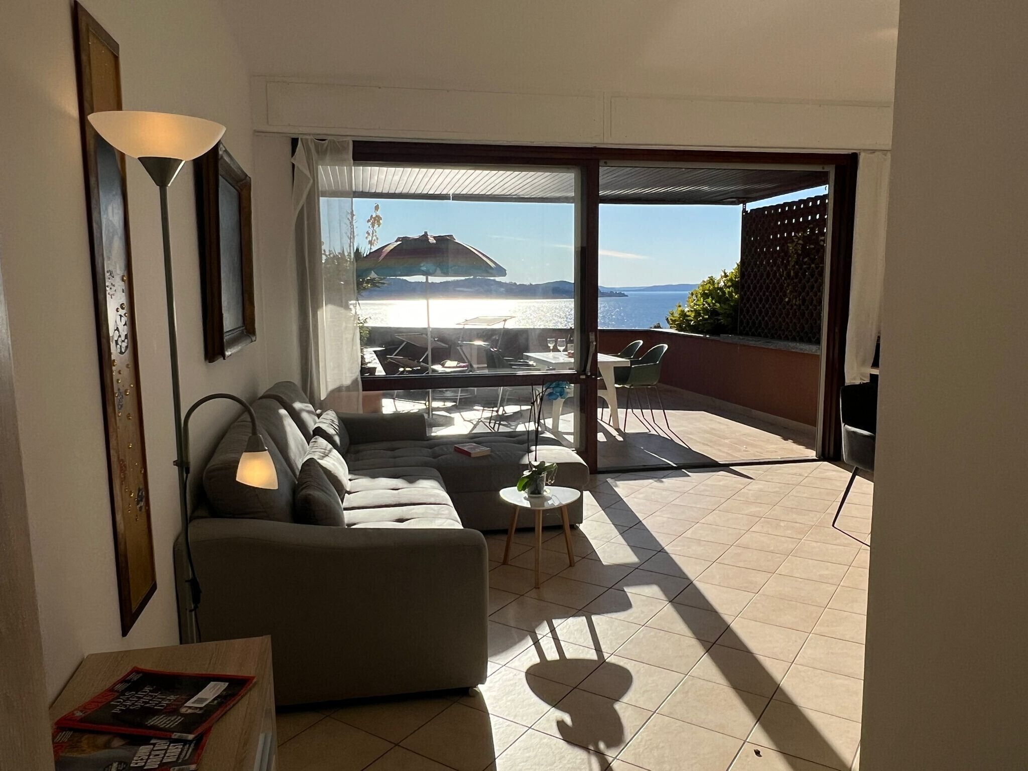 Una sala de estar con un sofá, una mesita y vista a un patio al aire libre con mesa y sillas.