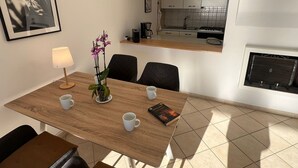 Een eetruimte met een houten tafel, stoelen, een potorkidee en een lijst met een foto aan de muur.