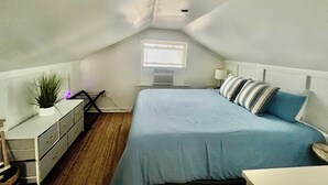 A small, sloped-roofed attic bedroom with a single bed, a dresser, a nightstand, and a window with blinds. - Sleeps 8-Cozy 3-Bedroom Cottage, 2 Blocks from the Strip, 10 Minutes from Spire (Geneva)