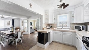 A spacious kitchen with white cabinetry, a built-in dishwasher, and a ceiling fan. - Sleeps 8-Cozy 3-Bedroom Cottage, 2 Blocks from the Strip, 10 Minutes from Spire (Geneva)
