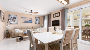 A modern living room with a sofa, dining table, and chairs, a ceiling fan, and artwork on the walls. - Home2Book Luxury Villa Pool & Terrace, Corralejo (Corralejo)