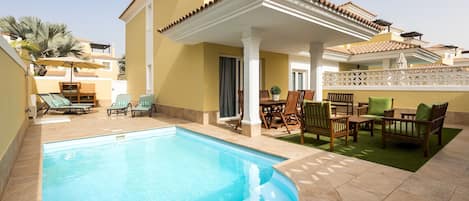 A swimming pool with lounge chairs and a covered patio area.