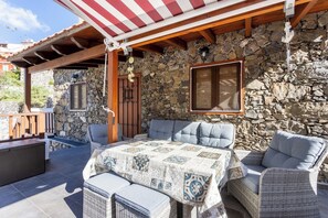 An outdoor patio with wicker furniture, a stone wall, and a wooden pergola. - Home2Book Valley Views & Private Terrace Hermigua (Hermigua)