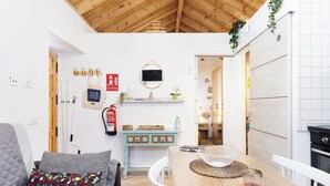 A cozy living room with a sofa, a coffee table, and a dining area with a table and chairs. There is a kitchen visible in the background with a stove and cabinets. - Home2Book Valley Views  & Private Terrace Hermigua (Hermigua)