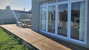 Ein modernes Haus mit Holzterrasse, großen Schiebegläsern und einer Solaranlage auf dem Dach.