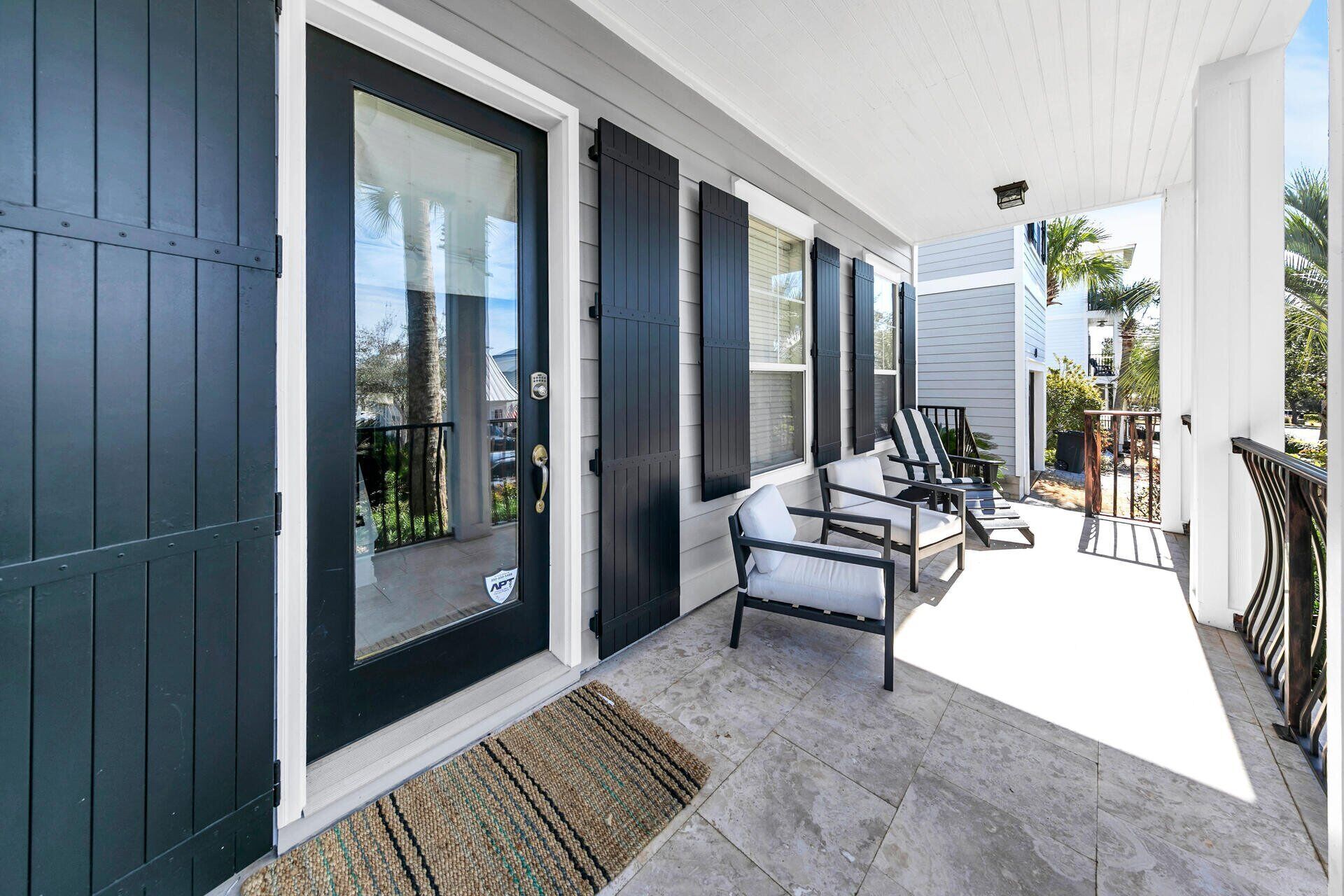 A covered porch with a seating area, a door with a glass panel, and a view of the surrounding neighborhood.