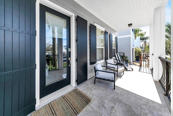 A covered porch with a seating area, a door with a glass panel, and a view of the surrounding neighborhood.