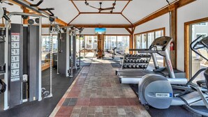 Un gimnasio con diversos equipos de ejercicio, incluyendo una cinta de correr, máquinas de pesas y un ventilador de techo.