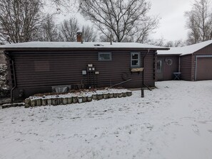 Une cabane en bois avec un toit enneigé, une petite fenêtre et une porte.