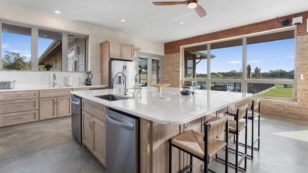 Una cocina moderna con una isla grande, electrodomésticos de acero inoxidable y vistas al exterior.