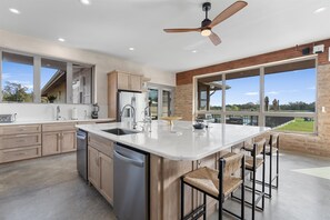 Una cocina moderna con una isla grande, electrodomésticos de acero inoxidable y vistas al exterior.