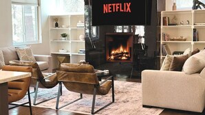 Una sala de estar con chimenea, televisor y estantería.