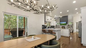 Una cocina moderna con una isla central, un comedor con mesa de madera y un ventanal con vistas a una terraza.