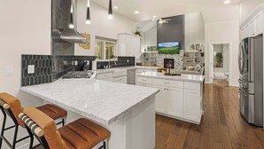 Una cocina moderna con una isla central, armarios blancos y un refrigerador grande.