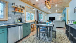 A modern kitchen with wooden cabinets, a dishwasher, and a dining area with a table and chairs.