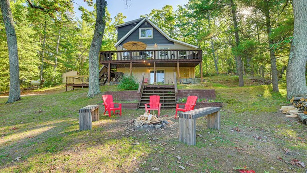 A cabin with a deck, outdoor seating, and a fire pit.