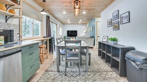A modern kitchen with a dining area, wooden ceiling, and a large window.