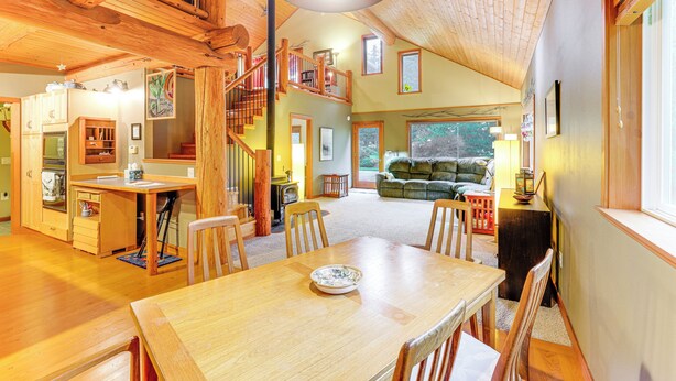 A spacious living area with a wooden dining table and chairs, a staircase leading to an upper level, and a cozy seating area with a sofa and a lamp. - 11 Mi to Olympic NP: Port Angeles Retreat w/ Deck (Port Angeles)