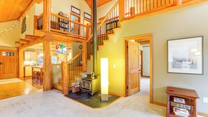 A spacious living area with a wooden staircase, a fireplace, and a bookshelf. - 11 Mi to Olympic NP: Port Angeles Retreat w/ Deck (Port Angeles)